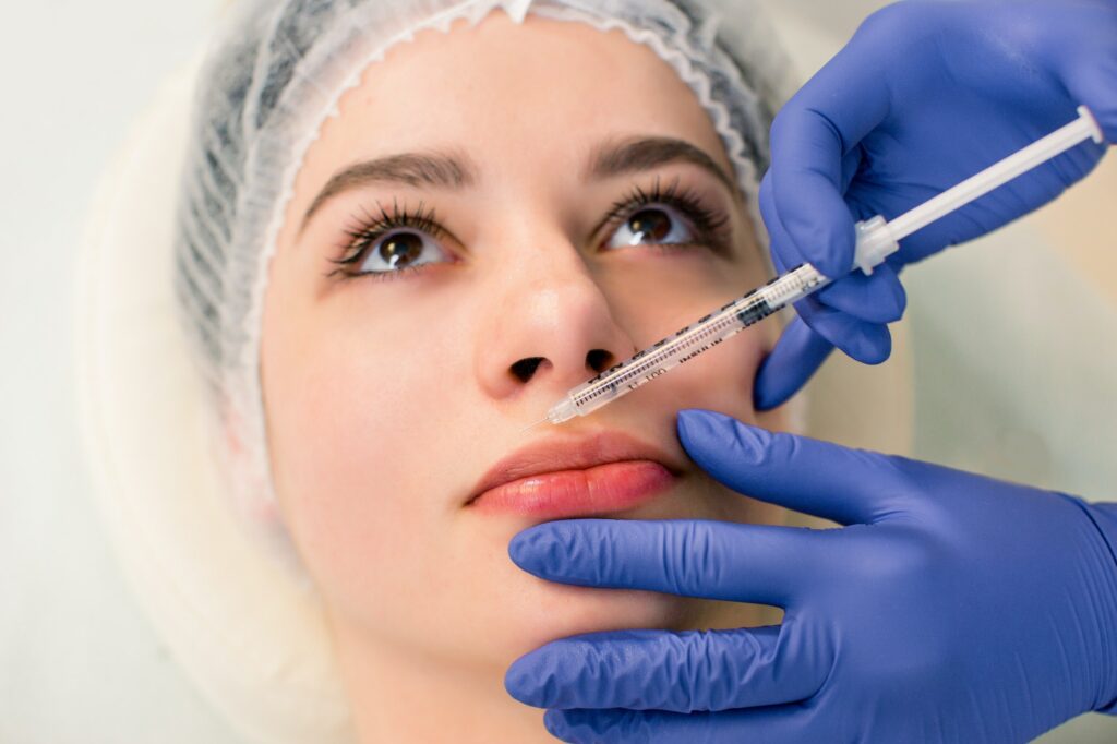 A beautiful woman receives a filler injection on the lips. Young woman receiving a botox injection