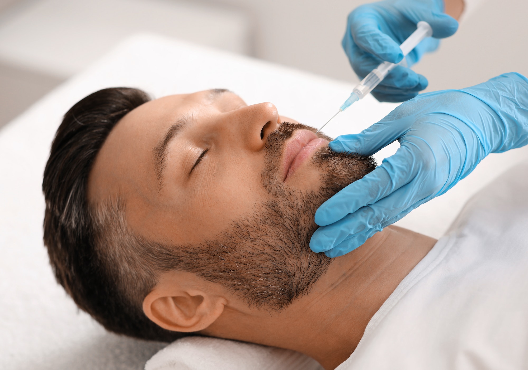 Attractive man visiting aesthetic clinic, getting lips filler