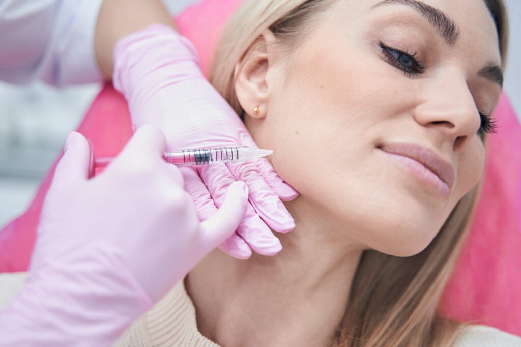 Female getting cheek filler injection under skin of cheekbone